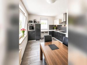 a kitchen with black cabinets and a wooden table at Apartment Wohnung „Sonnendeck“ by Interhome in Laupheim