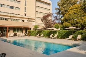 a swimming pool with chairs and umbrellas next to a building at Perugia Plaza Hotel in Perugia