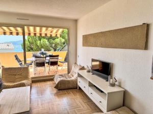 a living room with a television and a table with chairs at Apartment Cadet Rousse-6 by Interhome in Le Lavandou