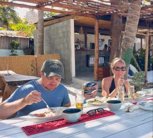 a man and a woman sitting at a table eating food at Bush Beach Hostel in Vilanculos