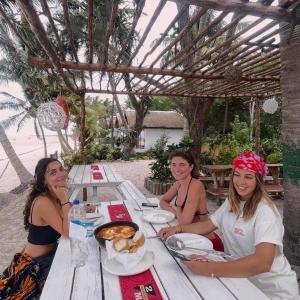 three women sitting at a picnic table with food at Bush Beach Hostel in Vilanculos +40 photos