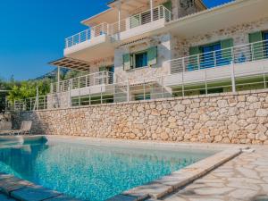 a house with a stone wall and a swimming pool at Petra & Thalassa in Plataria
