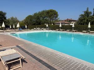 a large blue swimming pool with chairs and umbrellas at Tuscany Charme Apartments in Asciano