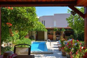 a swimming pool in a yard with flowers and a house at Villa Anthemida Chania in Ayiá
