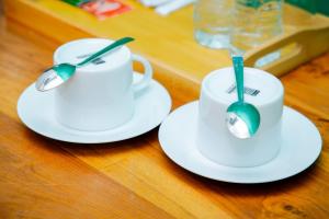 two white cups and spoons on a wooden table at JAI REST In in Jaffna