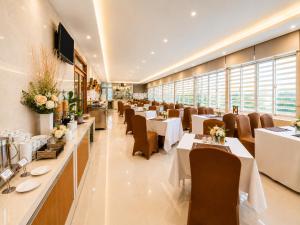 a restaurant with white tables and chairs and windows at G8 Diamond Hotel Saigon in Ho Chi Minh City