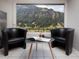 two chairs and a table with a book on it in front of a window at Holiday Home Chalet Guldeli by Interhome in Kandergrund +24 photos