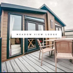a small house with a deck with a table and chairs at Meadow View Lodge in Tattershall