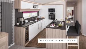 a kitchen with white cabinets and black counter tops at Meadow View Lodge in Tattershall