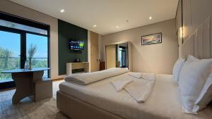 a bedroom with a large white bed and a window at Maskan Premium Hotel Tashkent in Aktepa-Chigatay
