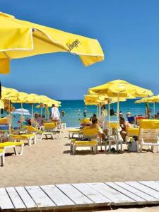 a group of people sitting on a beach with yellow umbrellas at Casa Bianca - Summer residency in Primorsko