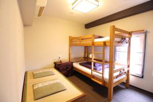 two bunk beds in a room with a window at K's House Tokyo Oasis - Quality Hostel in Asakusa in Tokyo