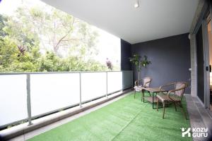 a balcony with a table and chairs and a green rug at KozyGuru | Epping | Stylish 1 Bedroom Apartment in Epping +4 photos