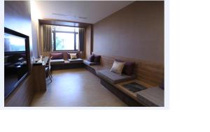 a living room with a couch and a television at Imperial Dynasty Boutique Hotel in Dounan