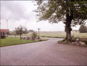 a brick road with a tree and wind turbines at Ferienwohnung Margarethe in Stedesdorf +5 photos