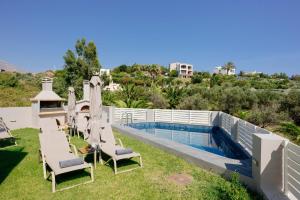 a backyard with a swimming pool and chairs and a swimming poolvisor at Lamon Villa in Plakias