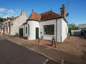 a white house with a green door on a street at Holiday Home Sullivan by Interhome in Drumnadrochit