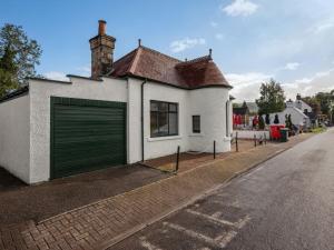 a white house with a green garage door on a street at Holiday Home Sullivan by Interhome in Drumnadrochit
