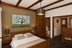 a bedroom with a bed and a tree painting on the wall at Goura Guesthouse Lake Doxa Mountain Retreats in Goura