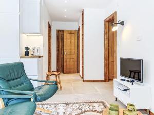 a living room with a green chair and a television at Apartment Le Sporting 213 by Interhome in Champex