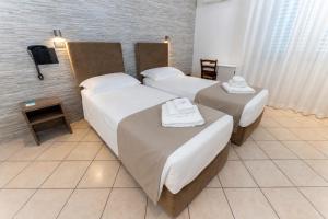 a hotel room with two beds with towels on them at Hotel Villa Itala in Rimini
