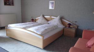 a bedroom with a wooden bed with white pillows at Landhaus Krinnenspitze in Nesselwängle