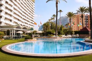 a large pool in a resort with palm trees and buildings at AR Roca Esmeralda & SPA Hotel in Calpe