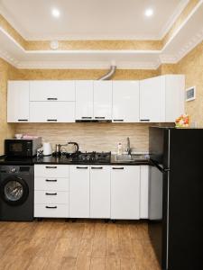 a kitchen with white cabinets and a black refrigerator at Historic Centre Apartment Kutaisi in Kutaisi