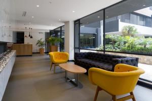 a living room with yellow chairs and a couch at Suites Metropoli Bristol Parc in Quito