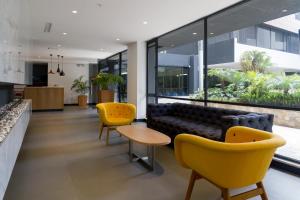 a living room with yellow chairs and a couch at Suites Metropoli Bristol Parc in Quito