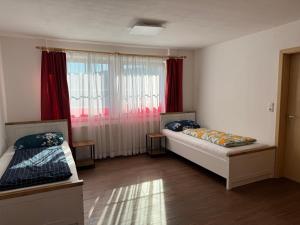 a room with two beds and a window with red curtains at Apartment Florence in Wettringen