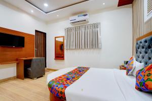 a bedroom with a bed and a desk and a television at FabHotel SV Grand I in Varanasi