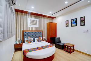 a bedroom with a large bed and a chair at FabHotel SV Grand I in Varanasi