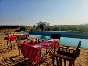 a table with a red checked table cloth and chairs next to a pool at Samburu Tempo Camp in Archers Post