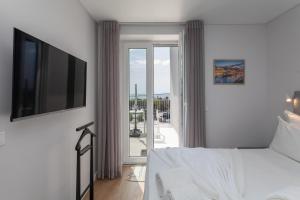 a bedroom with a bed and a television and a balcony at BeGuest Estoril Guesthouse in Estoril
