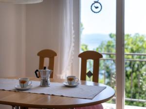 a table with two cups of coffee on it with a window at Holiday Home Orbani by Interhome in Lovran