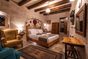 a bedroom with a bed and a chair and a table at Aren Cave Hotel And Art Gallery in Göreme