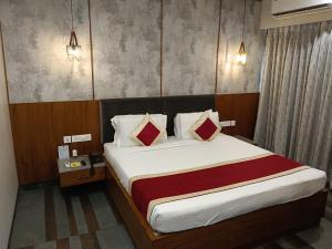 a bedroom with a bed with white sheets and red pillows at The Presidency in Bhubaneshwar +74 photos
