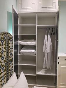 a walk in closet with white cabinets and towels at Njala Residence in Stantsiya Tekeli +4 photos