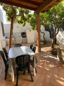 a table and chairs on a patio with trees at Casa Nespolo in San Vito lo Capo +4 photos
