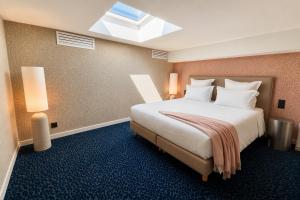 a hotel room with a large bed with white pillows at Flore Hôtel & Jardin The Originals Relais in Vichy