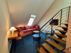 a living room with a red couch and stairs at Flore Hôtel & Jardin The Originals Relais in Vichy
