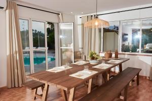 a dining room with a large wooden table with benches at Villa Raziel in Cártama