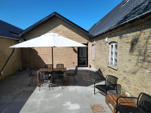 a patio with a table and chairs and an umbrella at Langemose Bed&Bath in Ringsted