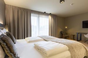 a bedroom with a large white bed with a window at Berg & Golf Resort Westendorf by ALPS RESORTS in Westendorf