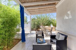 a patio with a blue canopy and chairs and tables at Masseria Prisuti in Punta Prosciutto