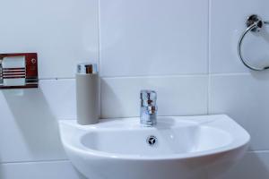 a white sink in a white tiled bathroom at Rustic Studio in CBD with free WI-FI in Nanyuki