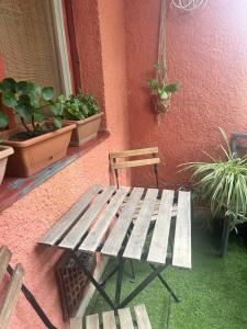 a wooden bench sitting next to a building with potted plants at Casa Siesta apartman in Makó