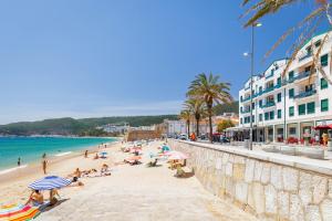 a beach with people sitting on the sand and the ocean at Casa da Praça - Alojamento Local in Sesimbra