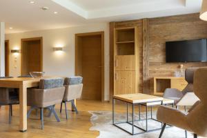 a living room with a table and chairs and a television at Berg & Golf Resort Westendorf by ALPS RESORTS in Westendorf